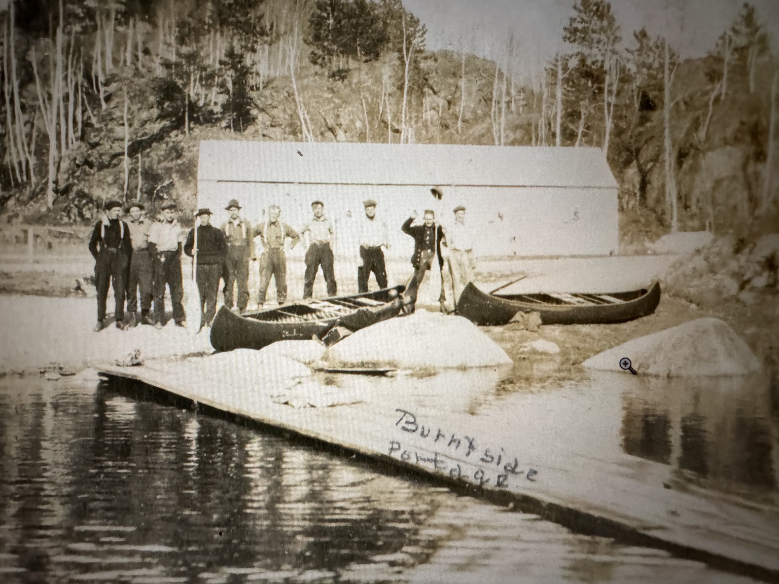 Historic group at a lakeshore landing beside two canoes. Andrew Hanson is among the people pictured; a handwritten Burntside caption appears on the print.